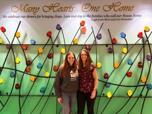 two women staning in front of donor wall