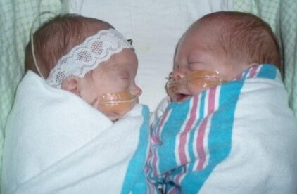 two preemie twins in crib together
