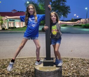 The Petrie girls balancing on a light pole.