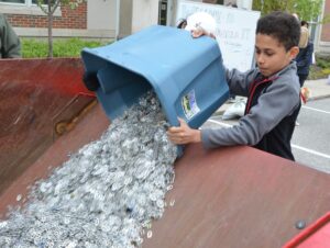 Little boy dumping pull tabs into dumpster