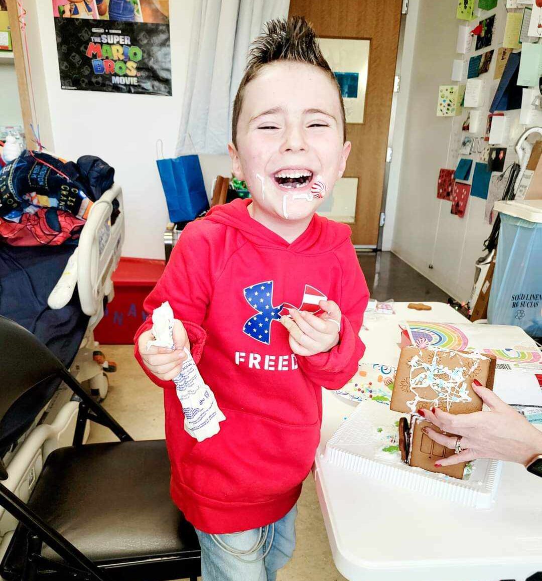 Boy laughing while decorating ginger bread house