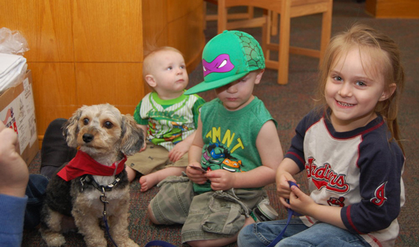 Three young children on floor with small therapy dog