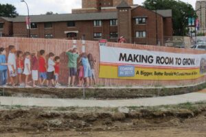 children peering through fence at construction