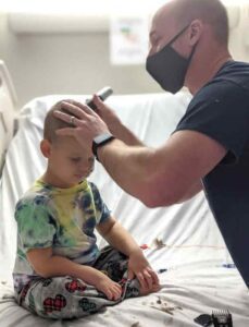 Father shaving childs head