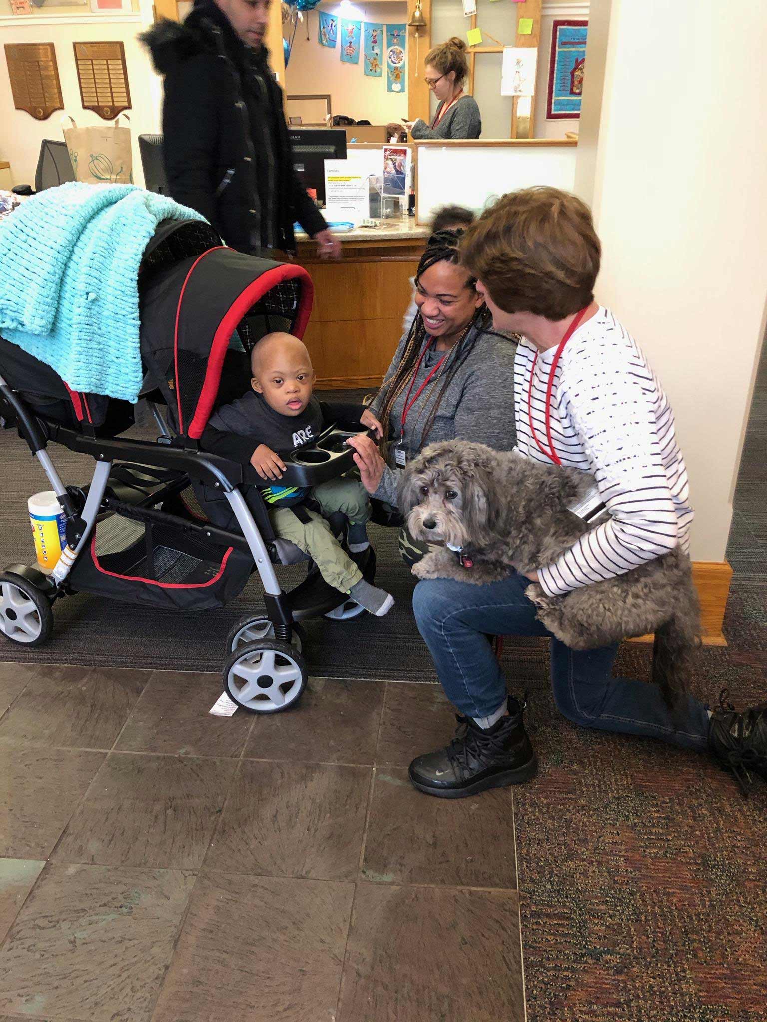 Boy in stroller, his mom and therapy dog with owner