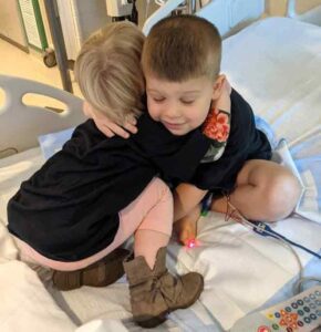 children hugging on hospital bed