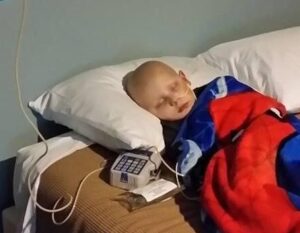 Billy sleeps in bed connected to an IV