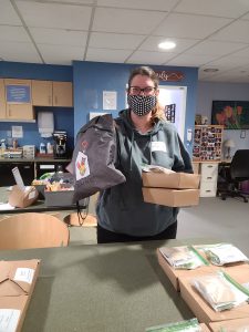 A young woman poses in front of the counter with two boxed lunches and an RMHC NEO knapsack.