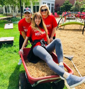 Three volunteers posing with a wheelbarrow full of mulch at the Cleveland House