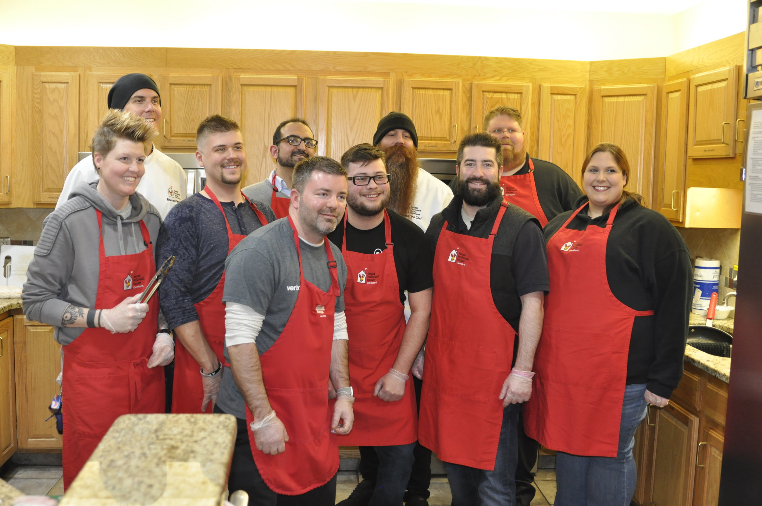 Group photo in the kitchen, wearing red aprons