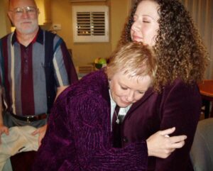 Donor's mother puts head on chest of heart recipient to listen to daughter's heart beat. Father stands in background