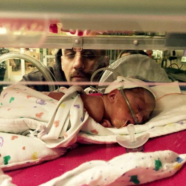 Dad looks at baby through incubator