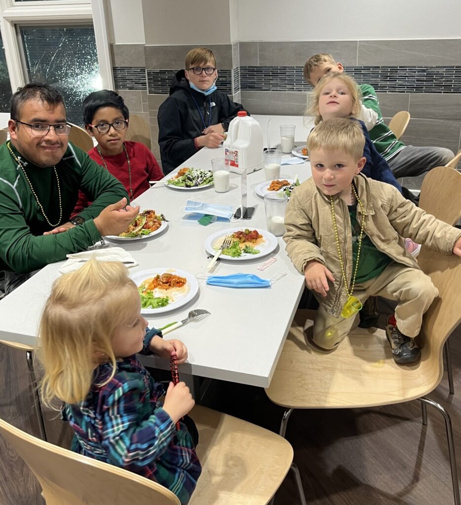 Sic children and adult eating a meal at long table