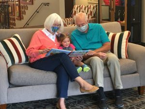 Grandparents sitting on a couch reading a picture book to a child in the lobby of Ronald McDonald house