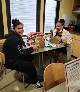 A new mom and grandma enjoying boxed lunches at a table in the kitchenette.