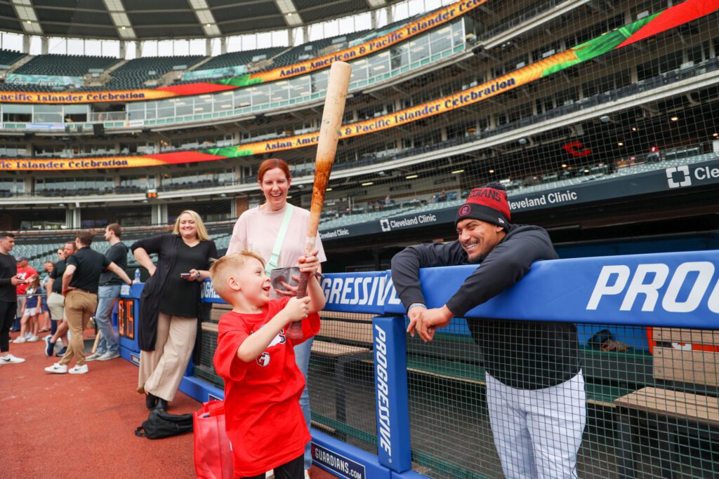 child holds bat given by baseball player in dugout