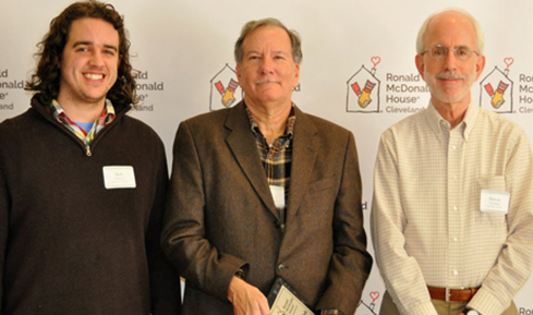 Three male Volunteers of Merit standing in front of RMHC backdrop