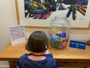 child facing table with Wish Hope Dream Jar full of colorful folded papers