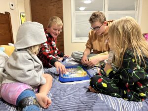Four children playing a game on a bed
