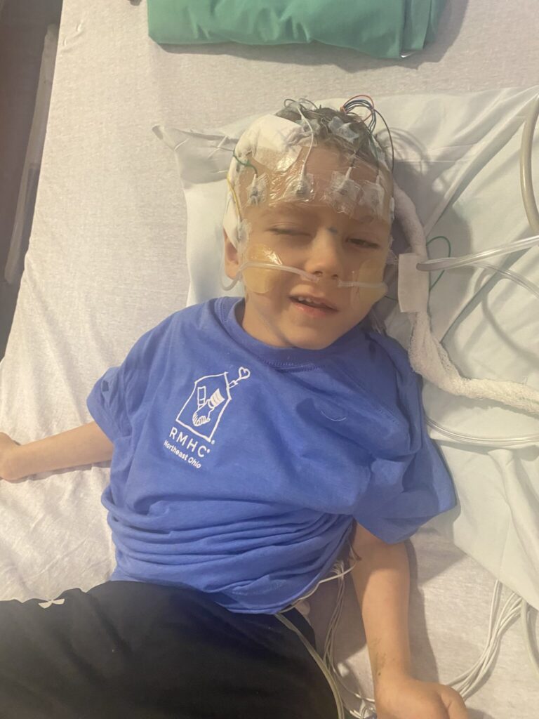child in hospital bed with electrodes on head and oxygen cannula