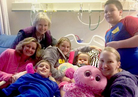 Two-year-old Shae in a hospital bed, surrounded by her family.