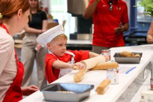 child in chef hat rolling crackers with rolling pin