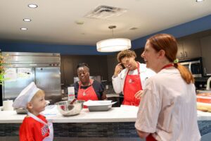 three adults and a child joyfully cooking in kitchen