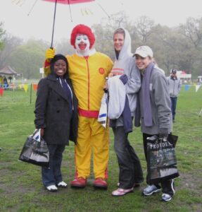 Three women walkers posing with Ronald McDonald clown in rain