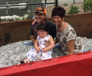 three individuals posing for photo in a full recycling container