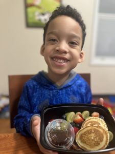 little boy smiling with breakfast foods