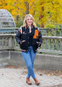 Girl wearing varsity jacket standing outside