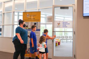 A woman with three children entering the spacious and sunny Ronald McDonald STAR Center.