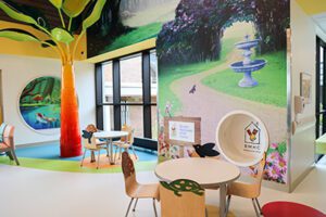 The Star Corner, with table, chairs, brightly painted wall murals, and a tree sculpture.