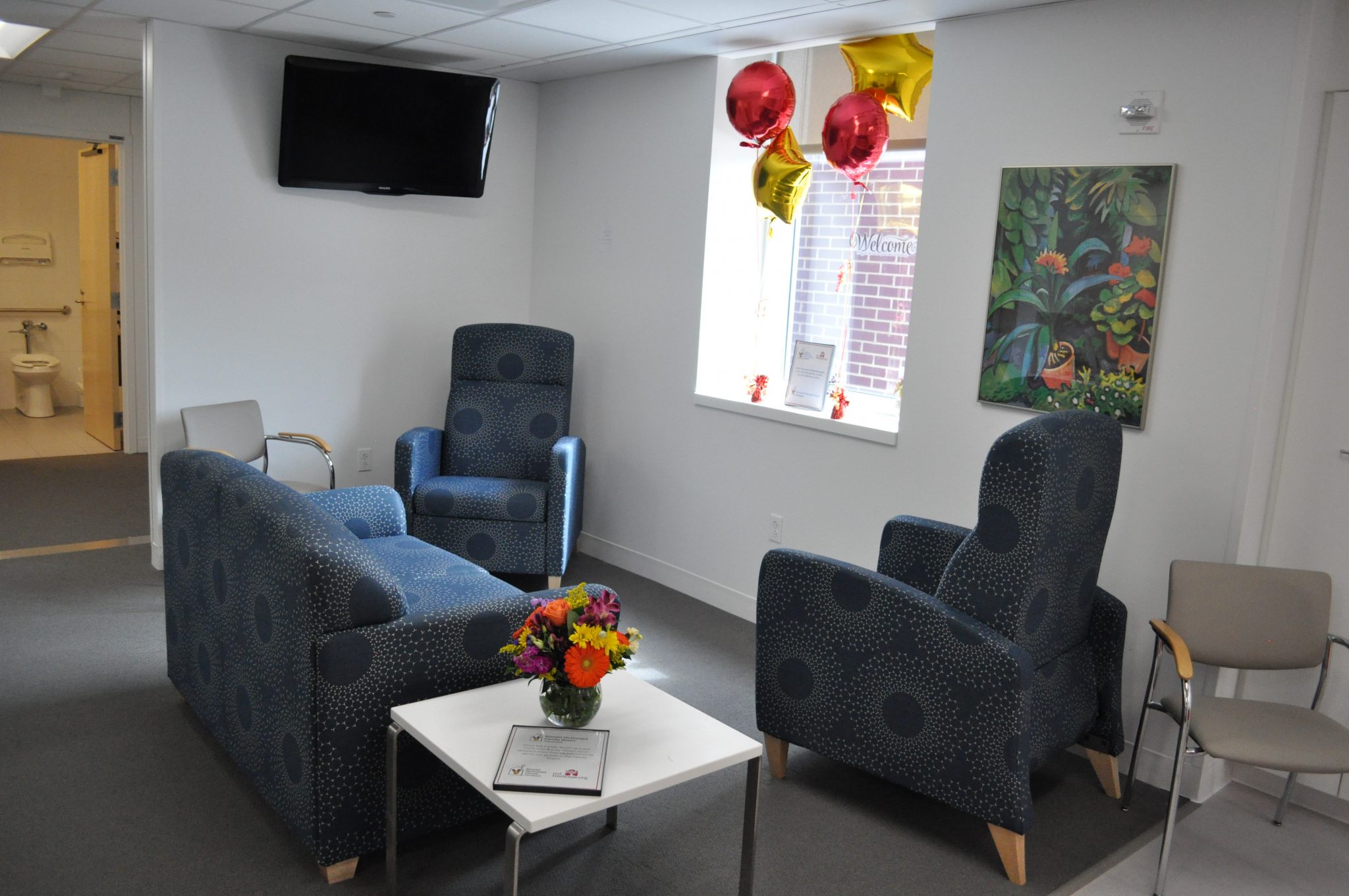 Seating area at the Fairview Family Room includes a blue couch and chairs, end tables, and television.