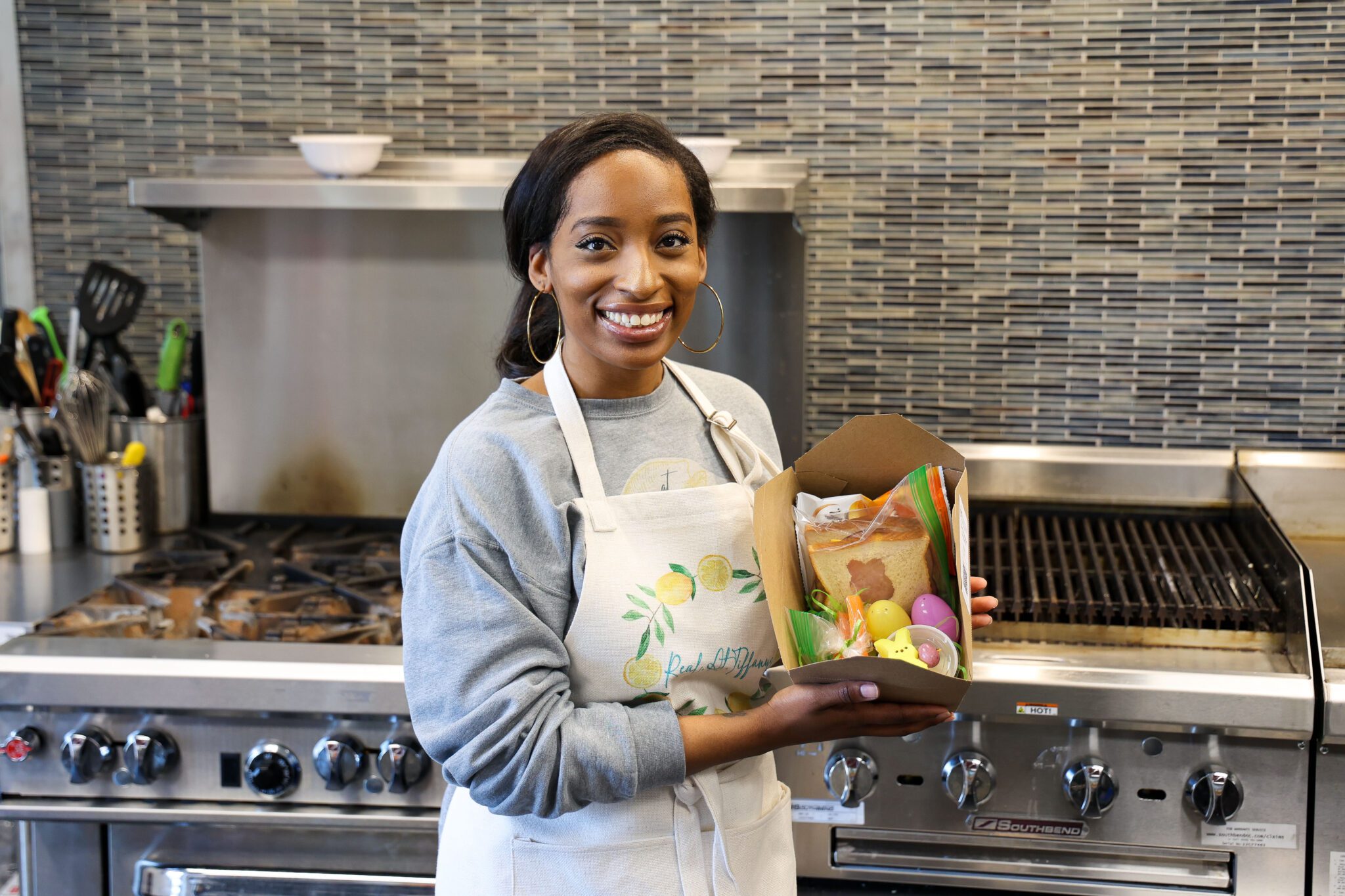 Volunteer in kitchen showing a boxed lunch,