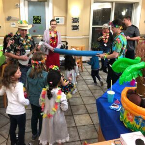 group of children and adults with leis and doing limbo