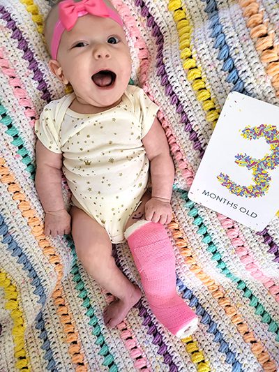 Haddie smiling with a pink leg cast and matching hair bow