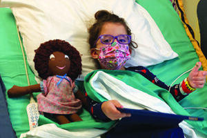 A little girl in a hospital bed with her doll
