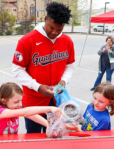 Oscar Gonzalez and two little girls dumping containers of pull tabs into a large bin