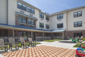 The outdoor patio next to playground has Adirondack chairs for seating.