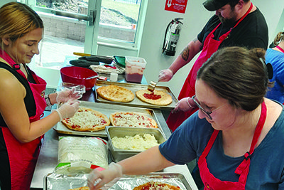 Volunteers make pizzas