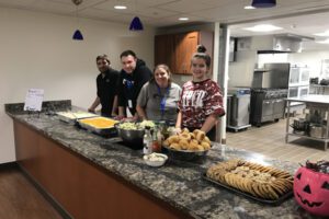 Volunteers serving prepared food for families. The commercial kitchen can be seen in the background.