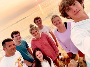 Shae with her parents and siblings, taking a group selfie on the beach