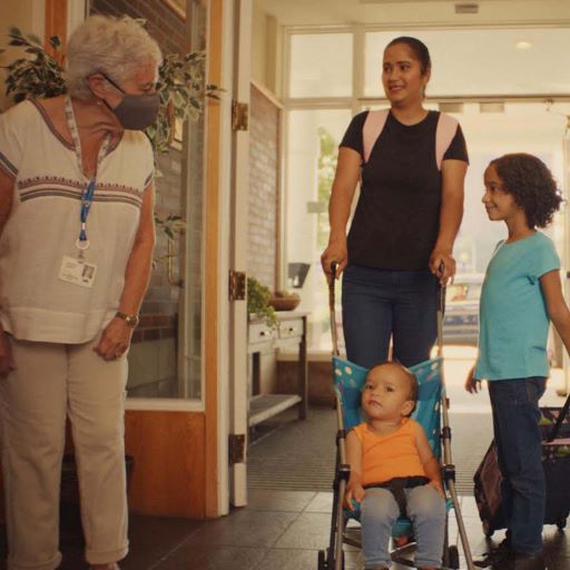 RMHC Welcome A volunteer welcoming a woman, child and toddler to the House