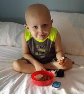 Billy with his feeding tube, sitting in bed.